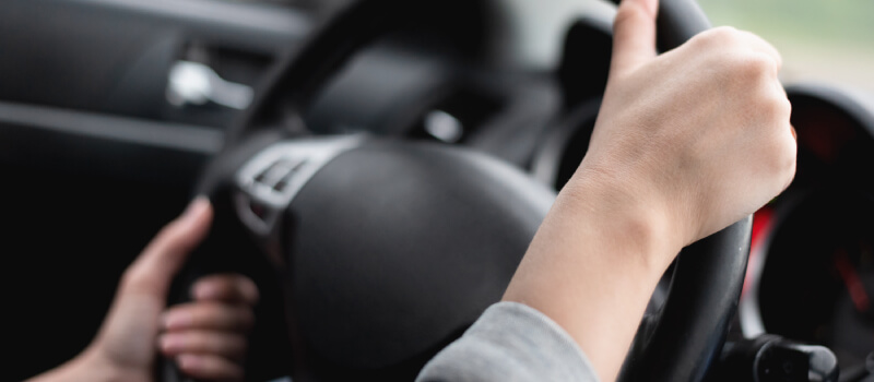 Both hands turning the steering wheel to the left