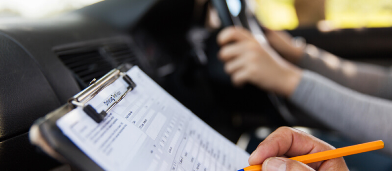 Examiner's hand marking a driving test sheet
