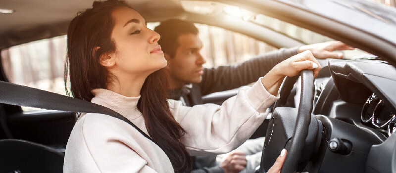 Instructor pointing across the dashboard to guide the learner driver