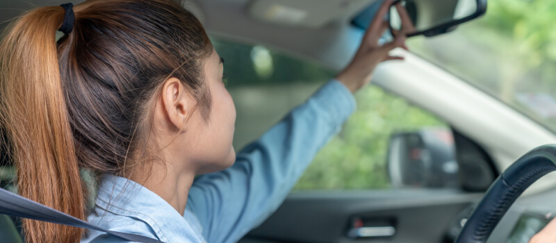Girl reaching to the rearview mirror
