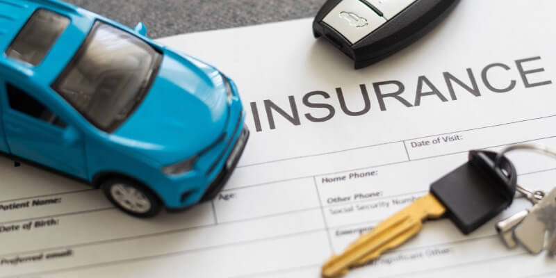 Insurance document with car key and toy car on top
