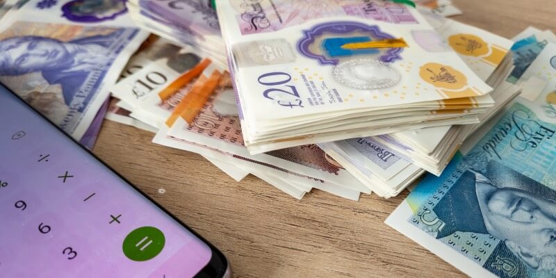 Stack of UK bank notes with a calculator beside them